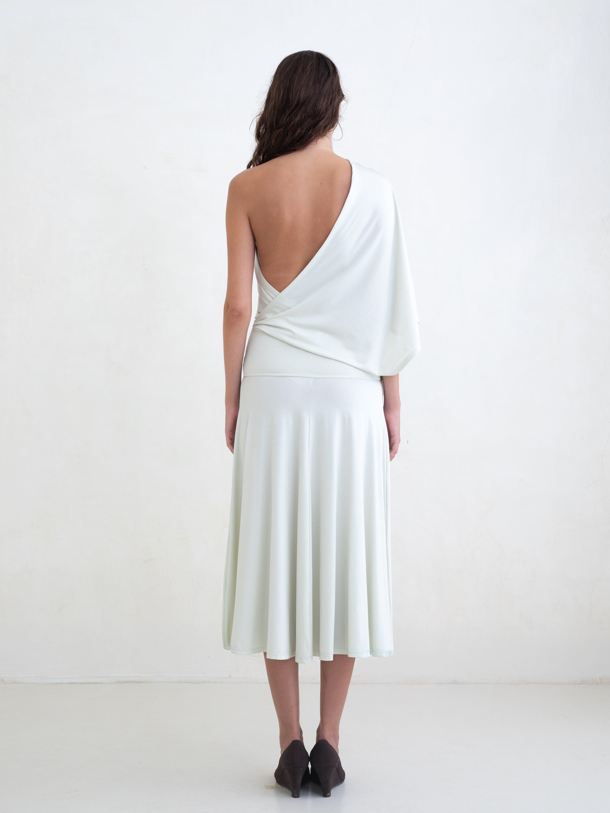 Woman wearing a light green one-shoulder midi dress on a white background 