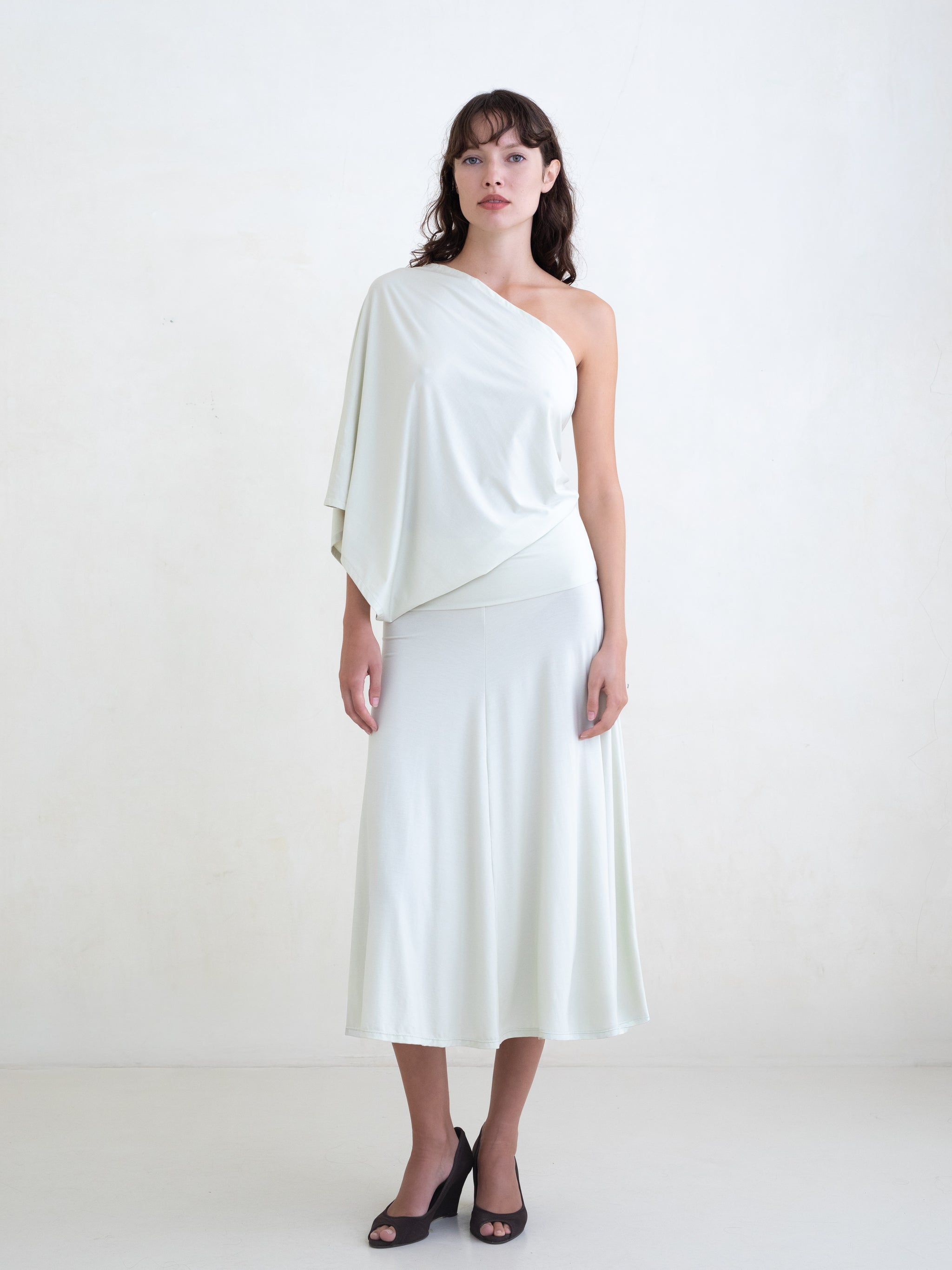 Woman wearing a light green one-shoulder midi dress on a white background 