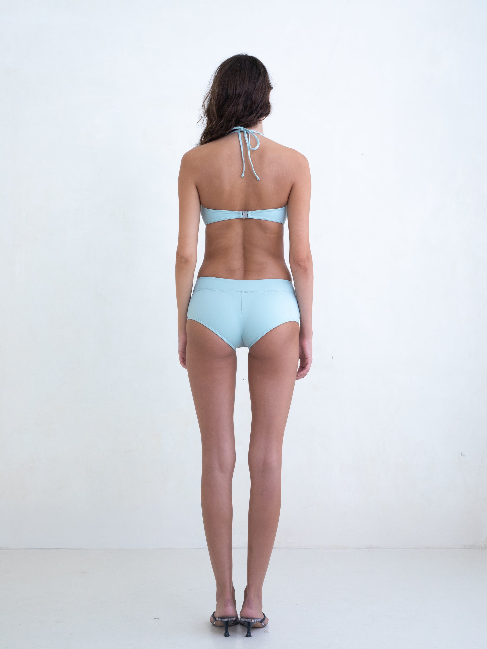 Woman wearing a light blue bikini on a white background. 