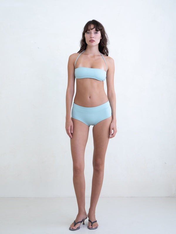 Woman wearing a light blue bikini on a white background. 
