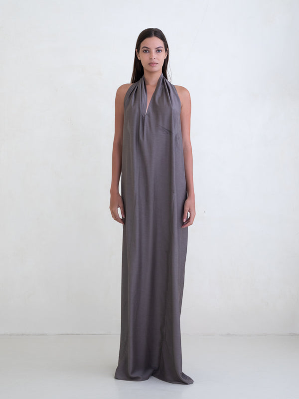 Woman wearing a taupe sleeveless maxi dress on a white background
